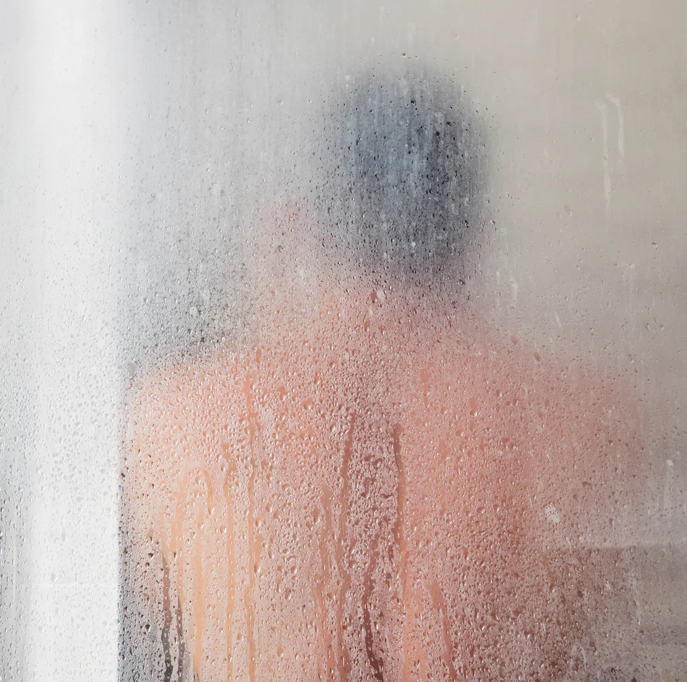 Mann in einer Dusche mit beschlagener Scheibe